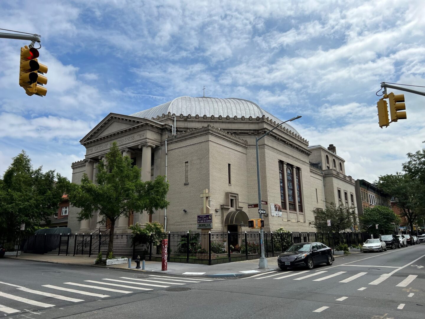 A large building with a dome roof on the corner of a street.
